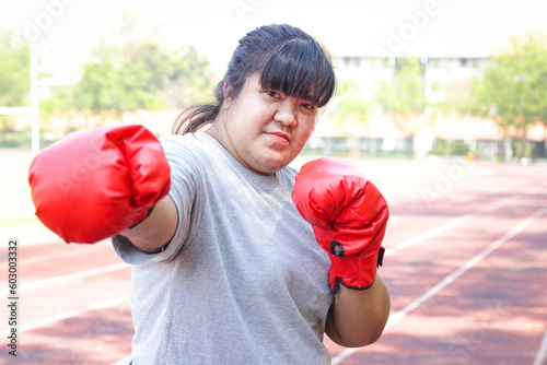 Fat Asian woman wearing red boxing gloves doing morning exercises. sports concept © SUPERMAO