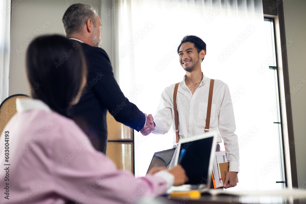 Business senior people shaking hands on business cooperation agreement. Successful hand shaking after good deal. Young Asian hipster male employee during job interview at office workplace