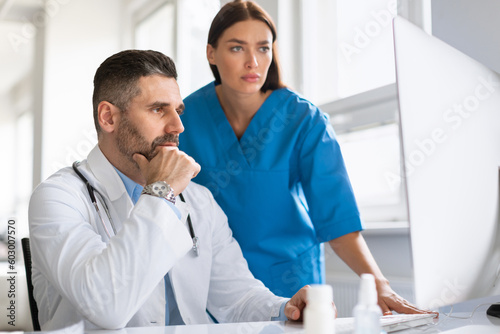 Diagnosis discussion. Focused male doctor and his assistant analyzing medical conditions using computer in clinic