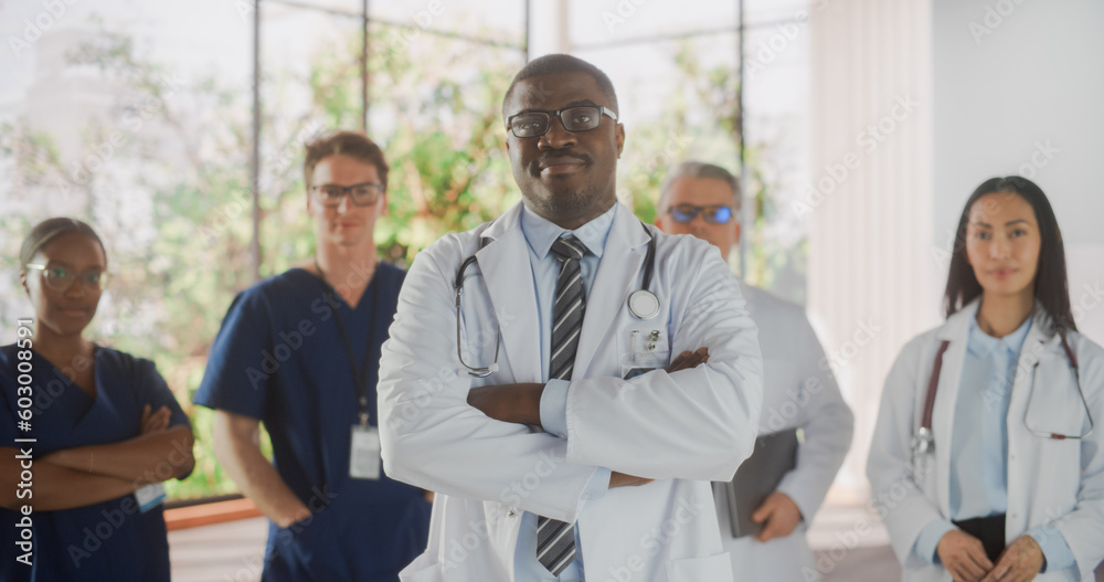 Team Portrait of a Female and Male Successful Diverse Medical Healthcare Professionals Standing as a Group in a Modern Hospital Office. African American Doctor Standing Closer to Camera Team Portrait of a Female and Male Successful Diverse Medical Healthcare Professionals Standing as a Group in a Modern Hospital Office. African American Doctor Standing Closer to Camera