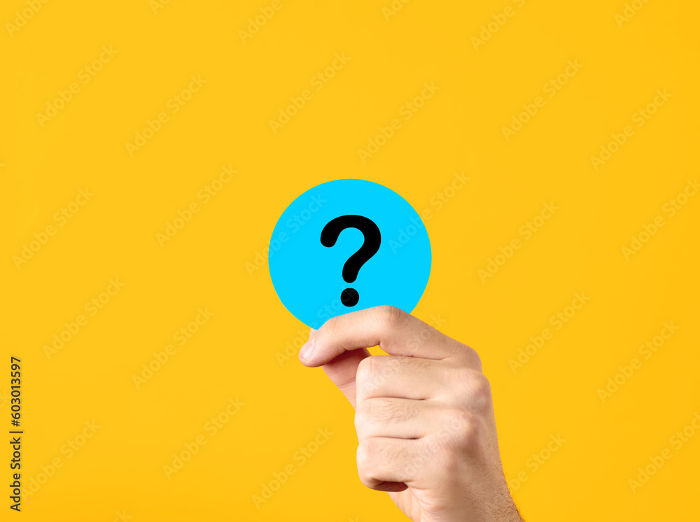 Problem, solution, uncertainty and confusion. FAQ frequently asked questions. Male hand showing a blue circle with question mark symbol on yellow background. Problem, solution, uncertainty and confusion. FAQ frequently asked questions. Male hand showing a blue circle with question mark symbol on yellow background.