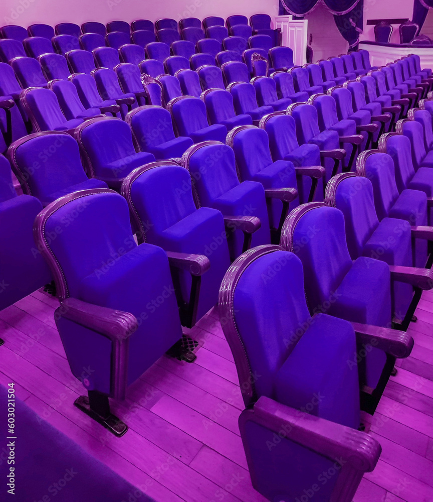 Fototapeta premium An empty modern cinema or conference room with rows of chairs, neon tinting
