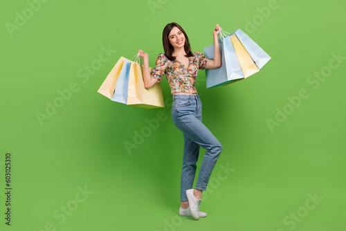 Full body photo of young funny fashionista shopaholic addiction girl raise hands with packages bags isolated on green color background