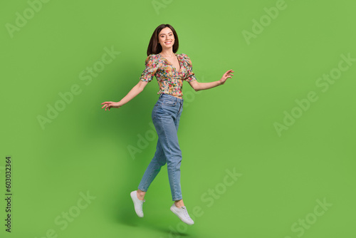 Full size profile portrait of cheerful excited girl jumping have good mood isolated on green color background