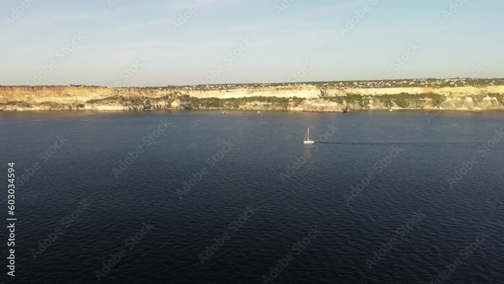 aerial view of a luxury sailing ship, with white sails, in the sea in the evening sunlight. luxurious summer adventure on a sailboat, offering an active vacation. aerial view of a luxury sailing ship, with white sails, in the sea in the evening sunlight. luxurious summer adventure on a sailboat, offering an active vacation.