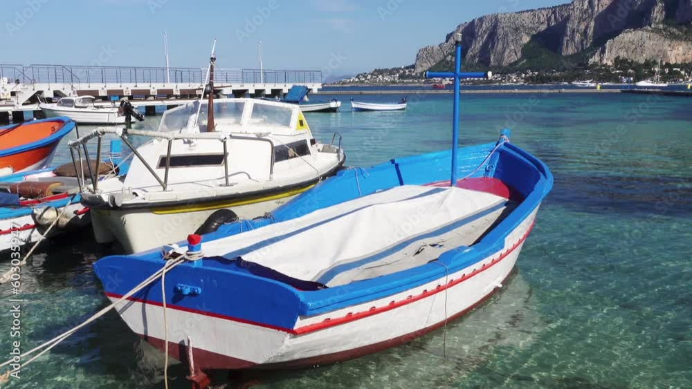 Boats moored. Italy, Mediterranean blue sea water, Sicily. Tansparent turquoise blue sea water in summer in a resort town for summer vacations. Mondello, Palermo. Boats moored. Italy, Mediterranean blue sea water, Sicily. Tansparent turquoise blue sea water in summer in a resort town for summer vacations. Mondello, Palermo.