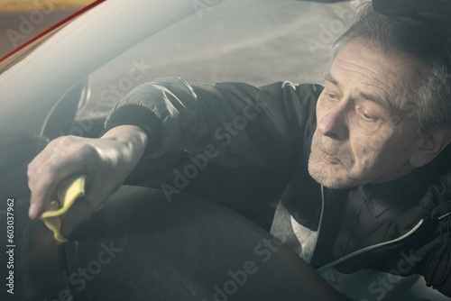 Older man take care annd cleaning car interior on nature parking photo