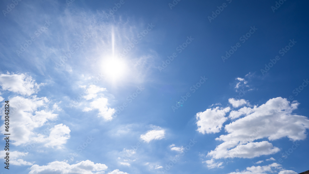 The bright sun with an overlay shines through the earth’s atmosphere. Beautiful blue sky with clouds and the sun in the midday.