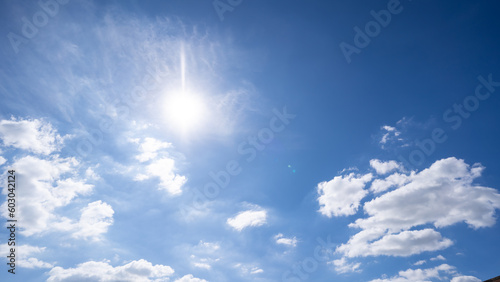 The bright sun with an overlay shines through the earth   s atmosphere. Beautiful blue sky with clouds and the sun in the midday.
