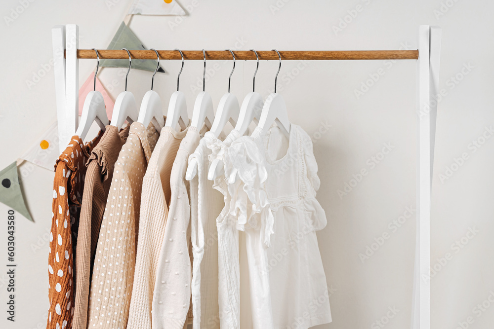 Fashion dresses and jumpers in white, beige and brown colors on hangers ...