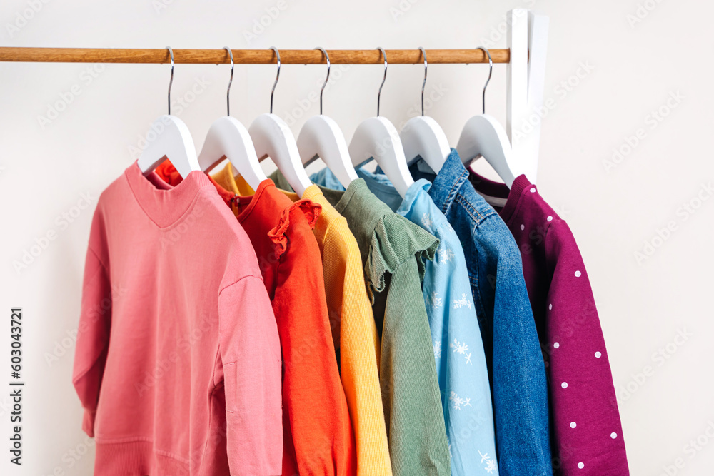 Clothing Rack with children's outfits close up. Fashion clothes in rainbow colors on hangers in wardrobe. Kids wardrobe. Set of kids clothes and accessories. Clothing Rack with children's outfits close up. Fashion clothes in rainbow colors on hangers in wardrobe. Kids wardrobe. Set of kids clothes and accessories.