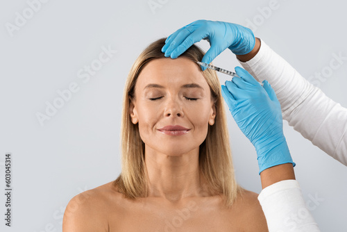 Middle aged woman getting cosmetic injection in her forehead, closeup