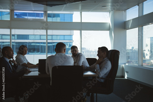 Silhouettes of people sitting at the table. Team of young business people working and communicating together in a modern office. Corporate team and manager in a meeting
