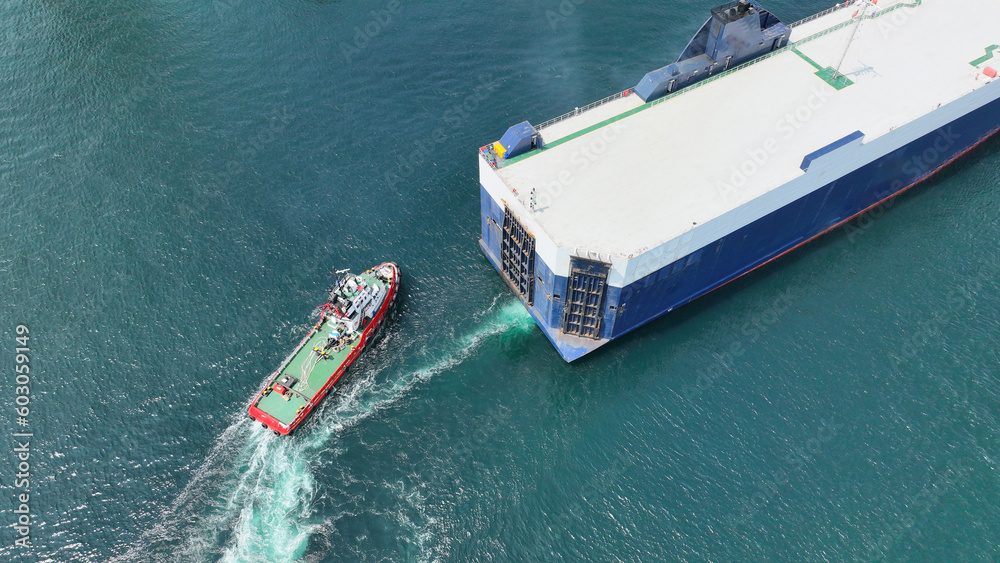Aerial drone photo of large car carrier ro ro vessel guided by tug boats to dock to Mediterranean port