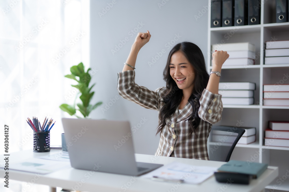 Happy asian businesswoman raising hands with victory smiling happily with laptop computer. The concept of success at work. Happy asian businesswoman raising hands with victory smiling happily with laptop computer. The concept of success at work.