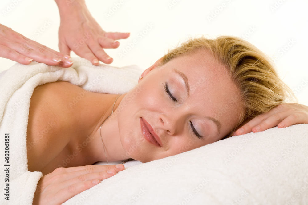 Attractive blond woman laying on stomach with a relaxed expression showing hands of another woman giving a massage Attractive blond woman laying on stomach with a relaxed expression showing hands of another woman giving a massage