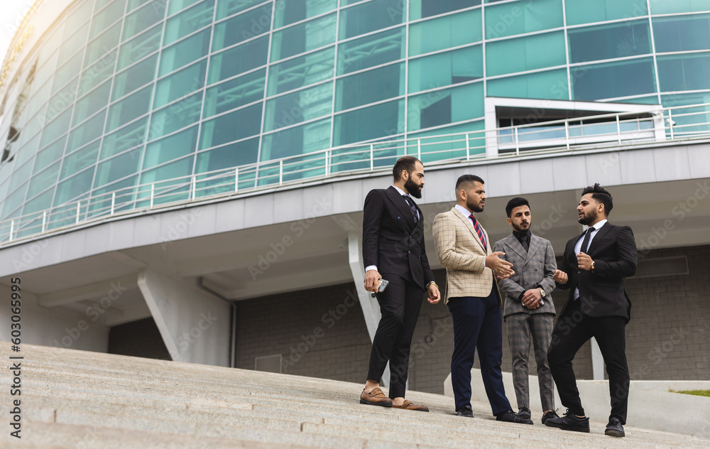 Business people outdoor meeting. A company of male businessmen in suits are sitting on the steps of the stairs. Working break. Teamwork and brainstorming. Successful teamwork Business people outdoor meeting. A company of male businessmen in suits are sitting on the steps of the stairs. Working break. Teamwork and brainstorming. Successful teamwork