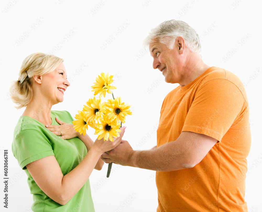 Middle-aged man giving woman bouquet of yellow flowers. Middle-aged man giving woman bouquet of yellow flowers.