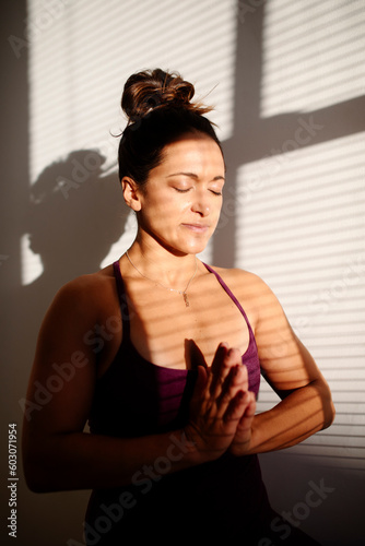 Portrait of woman doing prayer pose with shadows and sunlight photo