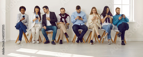 Group of different people using mobile phones. Male and female employees sitting in modern office with wireless Internet connection, looking at cellphone screens, messaging, and scrolling news feed