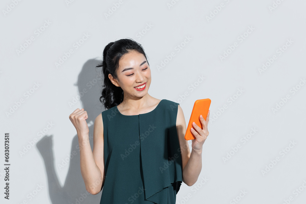 Young south asian woman using smartphone, celebrating victory Young south asian woman using smartphone, celebrating victory
