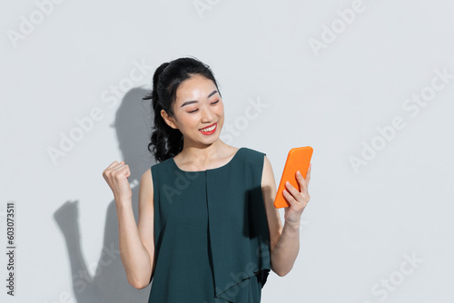 Young south asian woman using smartphone, celebrating victory photo