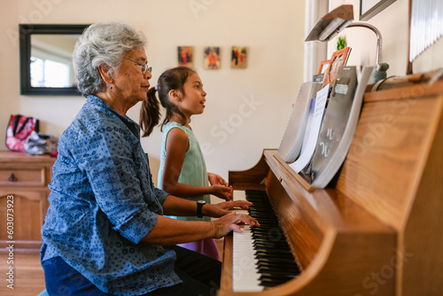 Woman plays piano while grandchild sings at home