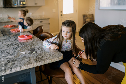 toddler girl with diabetes getting insulin shot in kitchen of her home