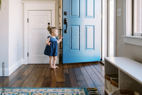 little girl holding door open at her home