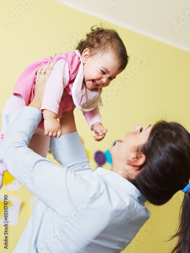 mom lifting her daughter up and smiling. Vertical shape