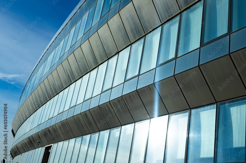 Obraz premium The blue sky is reflected in the windows of a modern office building. Architecture and exterior of contemporary houses