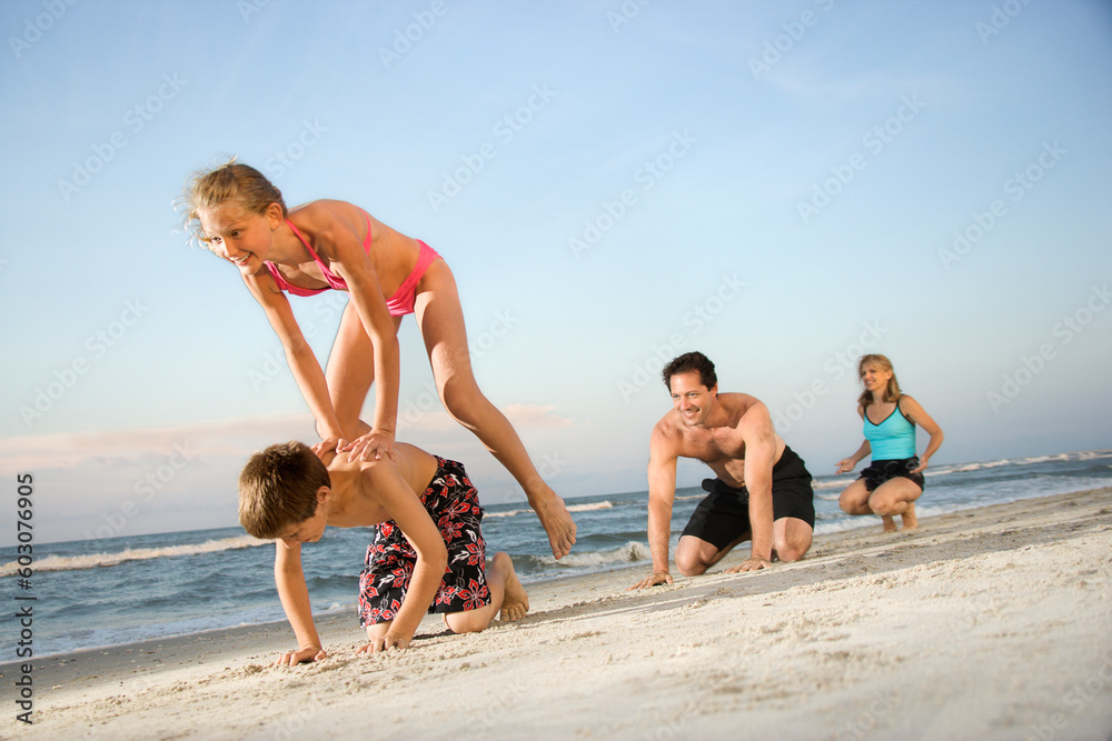 Family at the beach playing leap frog. Horizontal shot.