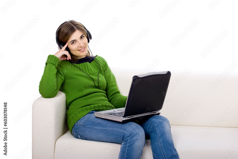 Young woman with headphones and a laptop, seated on a sofa isolated on white Young woman with headphones and a laptop, seated on a sofa isolated on white