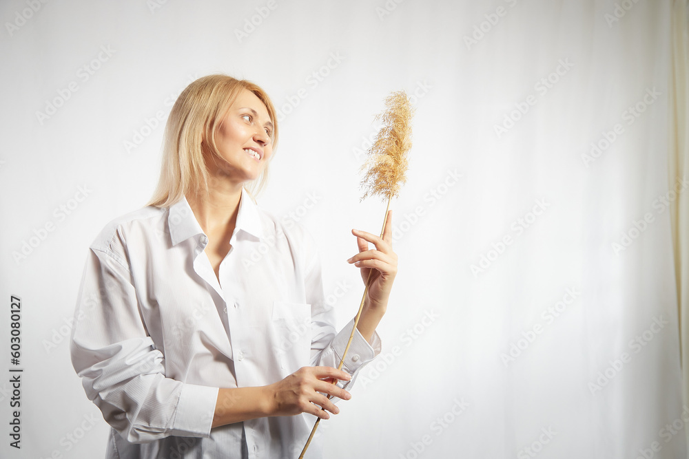 Portrait of a pretty blonde smiling woman with a soft ear in hands posing on a white background. Happy girl model in white shirt in studio. The concept of softness, tenderness and dreams. Copy space Portrait of a pretty blonde smiling woman with a soft ear in hands posing on a white background. Happy girl model in white shirt in studio. The concept of softness, tenderness and dreams. Copy space