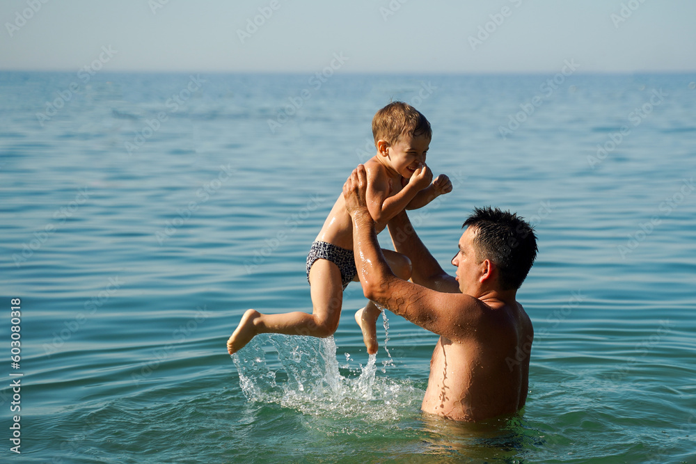 Dad and son splashing in the water merrily. Summer family vacations Dad and son splashing in the water merrily. Summer family vacations