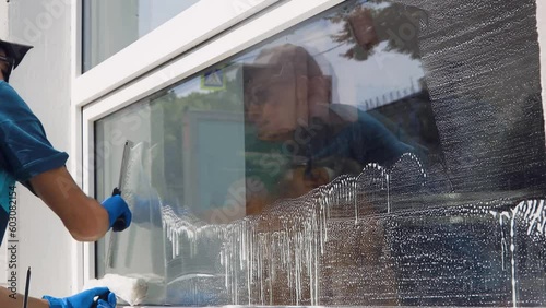 A professional worker from a cleaning company washes the company's windows with special chemicals