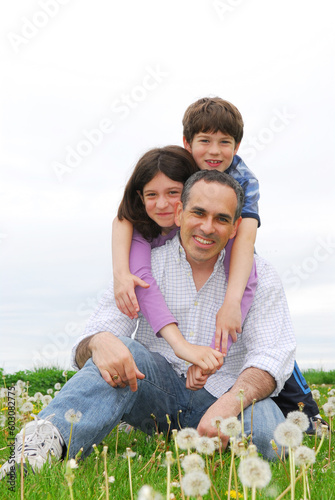 Portrait of a happy family of three on green grass © Designpics