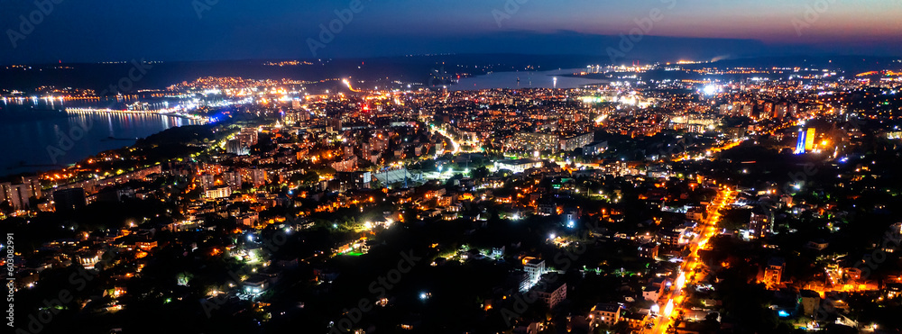 A panoramic aerial view of the city near the sea at night.