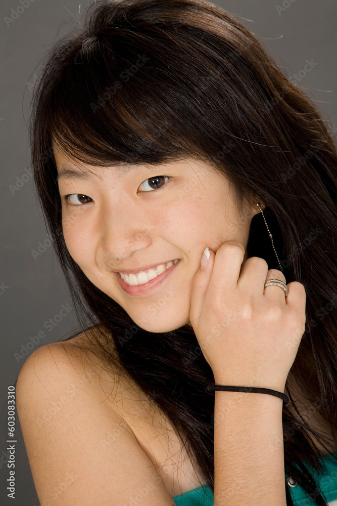 Portrait of a beautiful Asian teenager posing on a gray background with some attitude Portrait of a beautiful Asian teenager posing on a gray background with some attitude