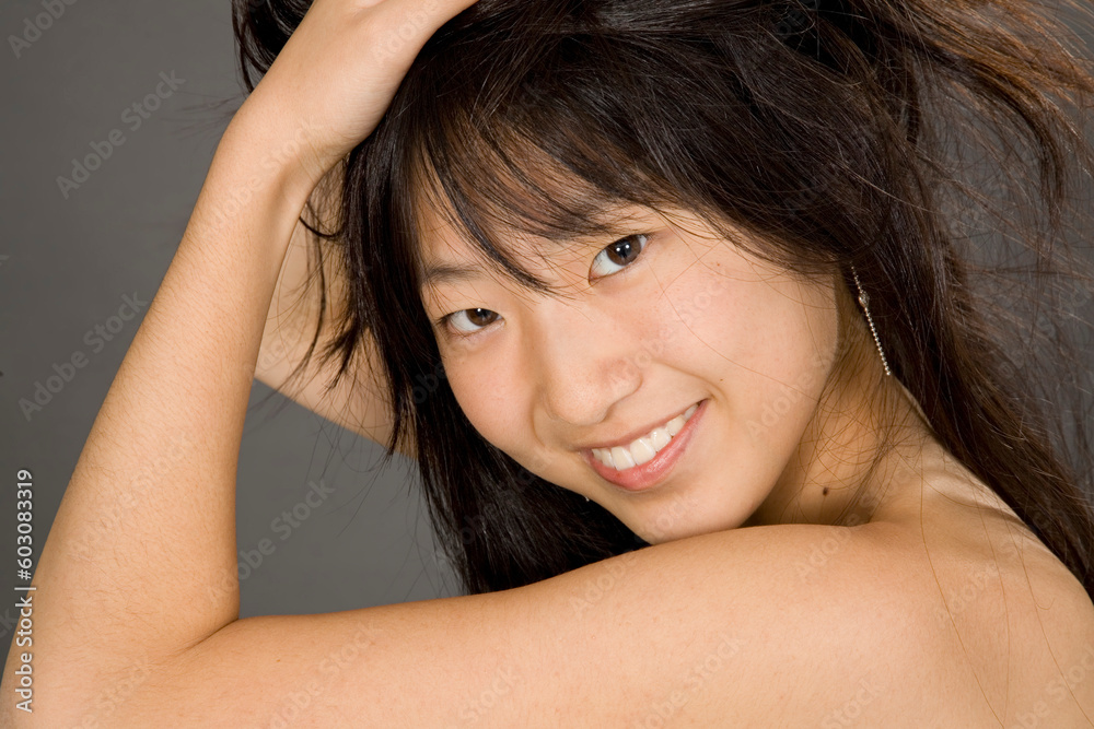 Fototapeta premium Portrait of a beautiful Asian teenager posing on a gray background with some attitude
