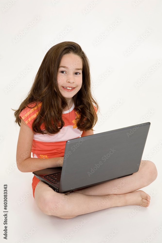 Young girl playing on a laptop computer on a white background Young girl playing on a laptop computer on a white background