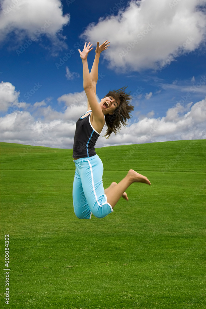 Beautiful happy woman jumping on a green field