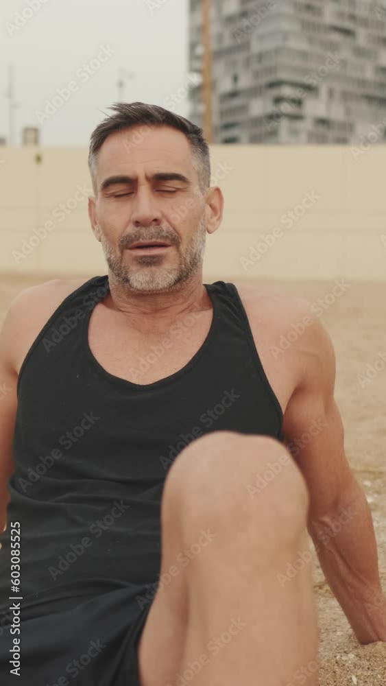 Mature man is resting sitting on the sand on the coast Mature man is resting sitting on the sand on the coast