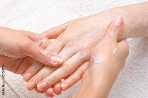 applying peeling scrub or moisturizing cream onto the hands