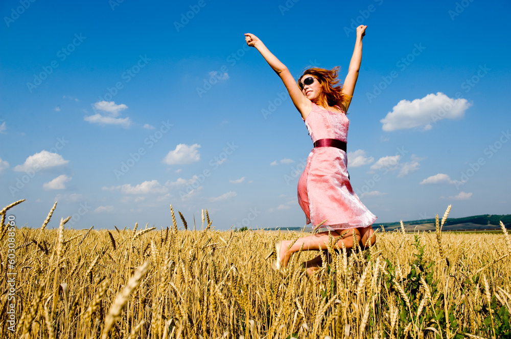 Happy woman wearing sunglasses jumping in golden field Happy woman wearing sunglasses jumping in golden field