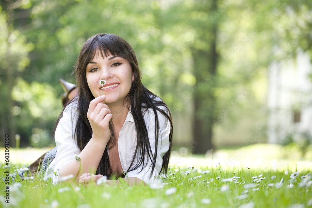 attractive brunette woman relaxing by lying on grass in park attractive brunette woman relaxing by lying on grass in park