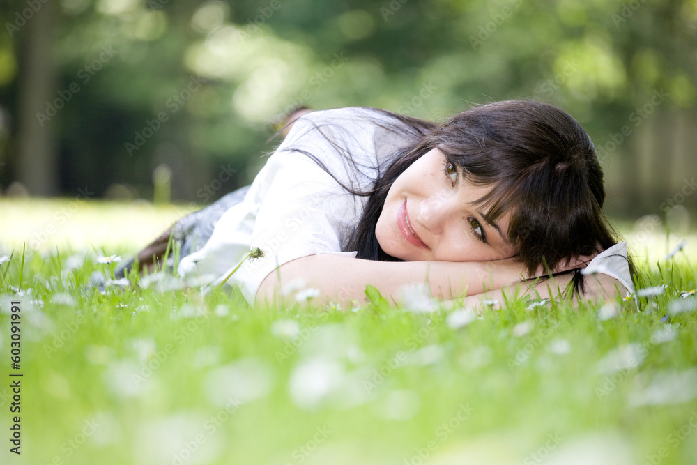 attractive brunette woman relaxing by lying on grass in park attractive brunette woman relaxing by lying on grass in park