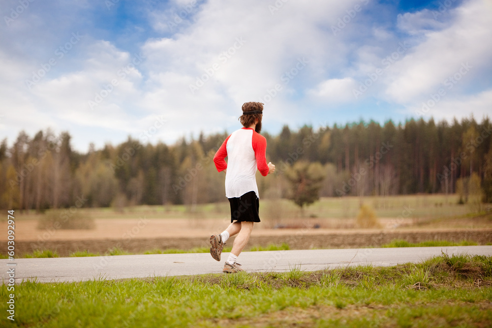 A runner with long hair and beard jogging in the country A runner with long hair and beard jogging in the country