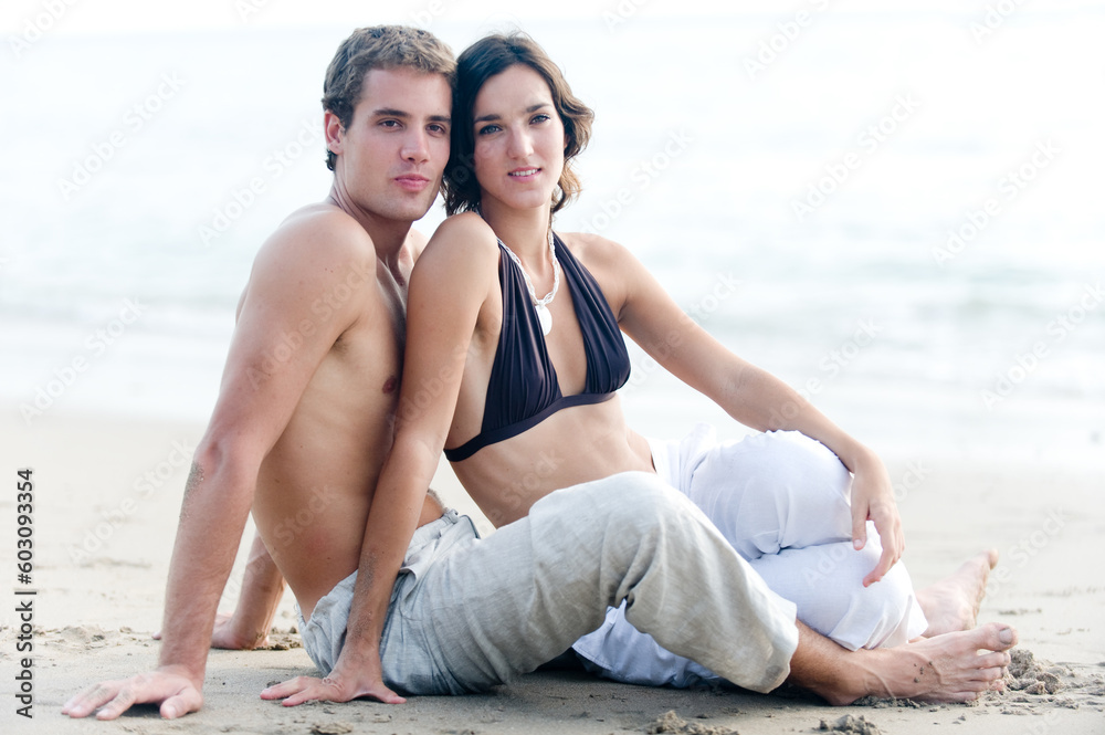Fototapeta premium A young couple sitting together on the beach