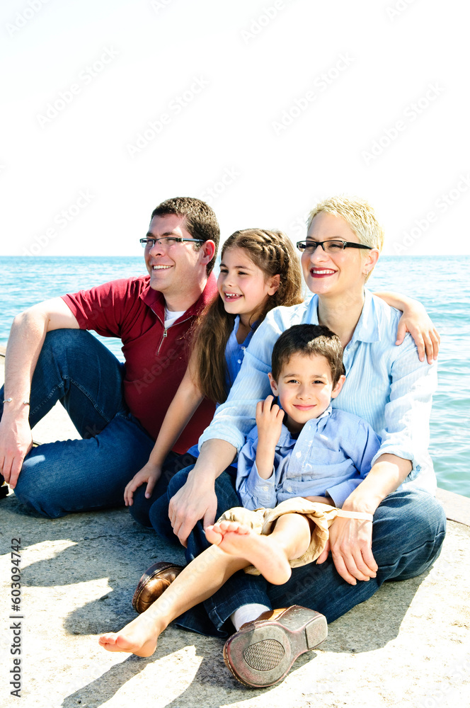 Happy family sitting on pier at lake